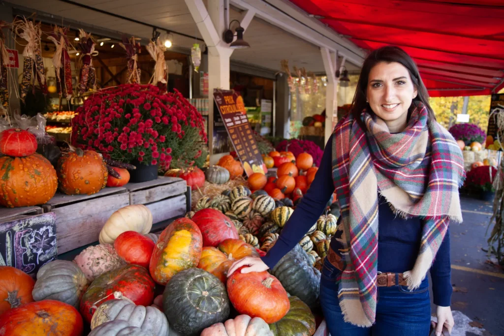 Keto coach Evelyne browsing fresh vegetables and pumpkins at an outdoor market