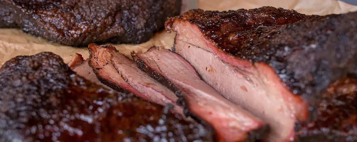 Perfectly sliced oven brisket with a dark bark, resting on a cutting board